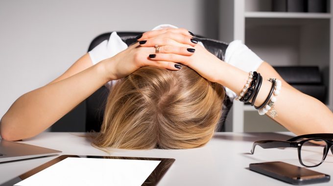 Woman With Head On Desk After Making Event Planning Mistakes